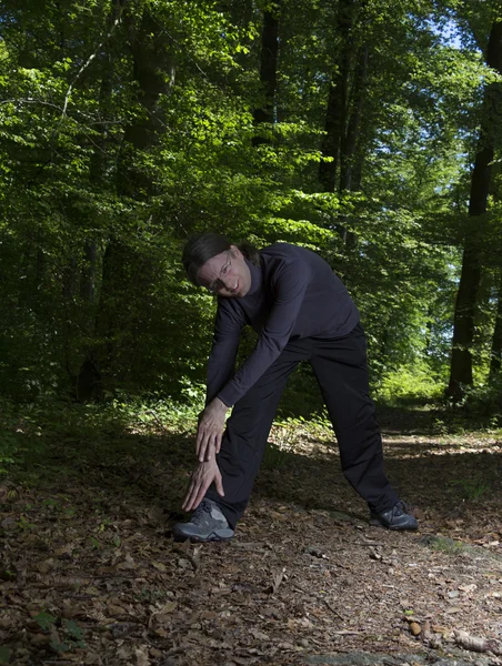 Stretching man in the forest — Stock Photo, Image
