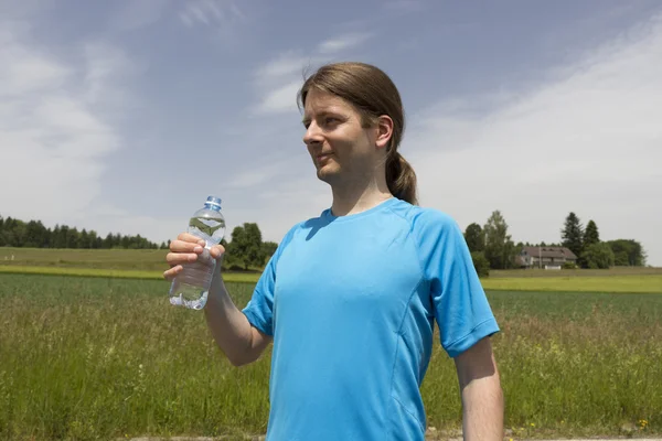 Sportlicher junger Mann im Freien mit einer Wasserflasche — Stockfoto