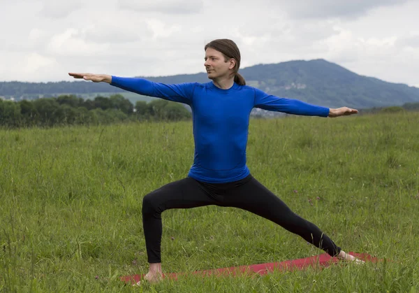 Homem em Guerreiro II Pose durante ioga ao ar livre — Fotografia de Stock