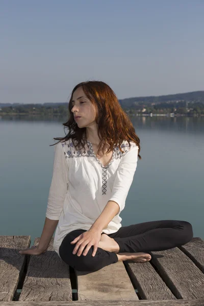 Mujer haciendo giro de columna vertebral sentado en la naturaleza durante el yoga —  Fotos de Stock