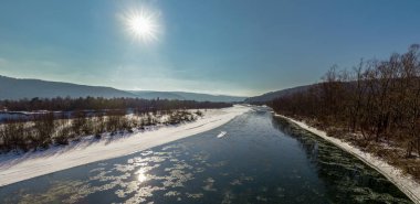 Kış dondurucu soğuk - panorama. Dağların üzerinde mavi gökyüzünde güneş ve soğuk bir kış gününde dağ nehri. Dağ nehri Stryi, Karpatlar, Ukrayna 'nın kış panoraması. 