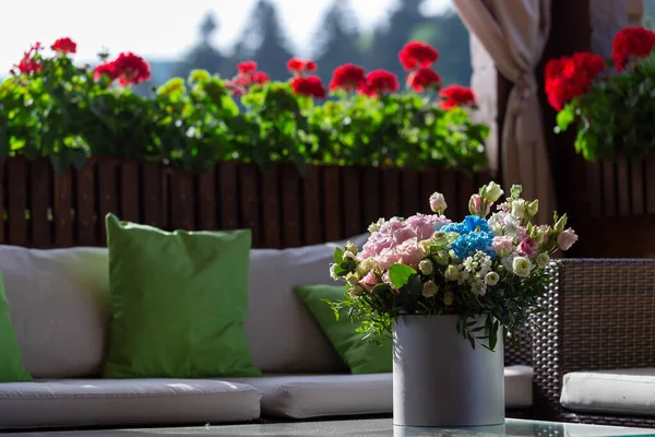 A rose bouquet in a box on a summer terrace. A bouquet of pink and white roses decorated in a hat box created by a florist.