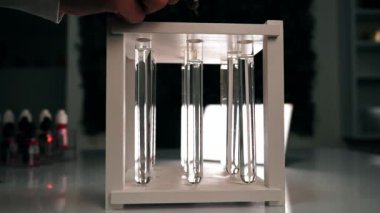 Bir bilim adamı, temiz bir sıvı şişesinin içine kimyasal bir portakal reaktörü damlatıyor. Kimyasal turuncu-kırmızı reaktör, temiz bir sıvıyla test tüpünde yavaşça erir. Ağır çekim. Yakın plan.