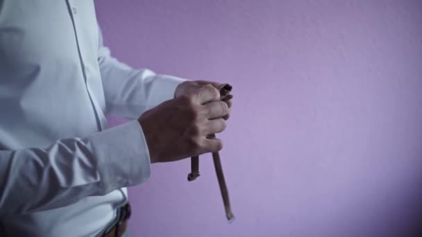 新郎的手在白色衬衫中的特写 将褐色领结系在紫色的墙上 — 图库视频影像