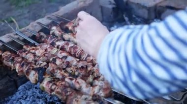 Bir adamın eline barbekü fırçası sürerek soslu kızarmış et sür. İnsan doğada kebap kızartır.