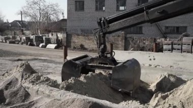 Huge black bucket, grabs sand and moves it to a large sand hangar. Black bucket grabs sand and moves it to concrete kneading tank at production site