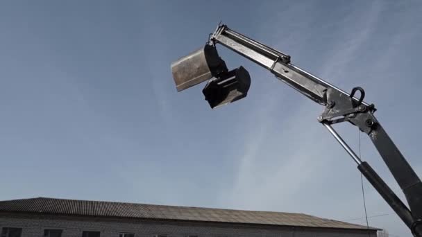 用空桶移动的黑色建筑用起重机在蓝天的衬托下装载建筑材料 — 图库视频影像