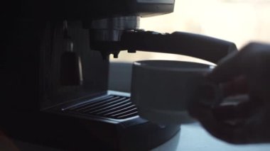 Bir adamın eline yakın çekim beyaz kupa koyar ve kahve makinesinde kahve yapar. Barista cappuccino veya espresso yapar.