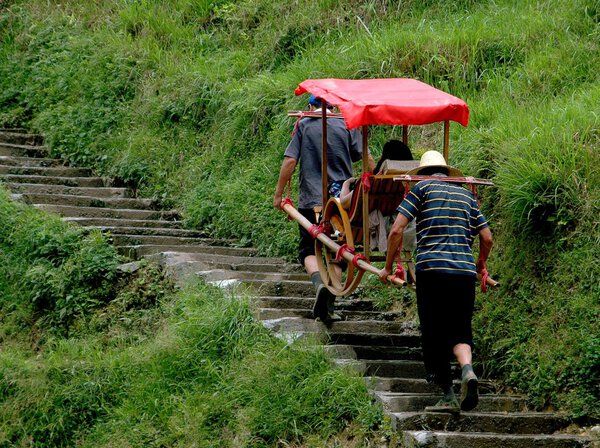 China: Porters Carrying Tourist in Sedan Chair at Longsheng
