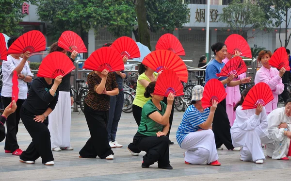 Pengzhou, China: Mujeres con abanicos rojos haciendo tai 'chi — Foto de Stock