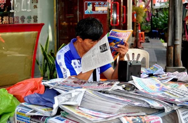 Bangkok, thailand: man leest magazine over yaoworat weg — Stockfoto
