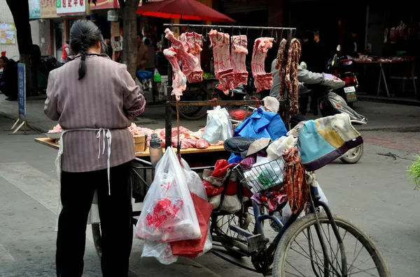 Pengzhou, China: Mujer vendiendo cerdo de su carro de la bicicleta — Foto de Stock