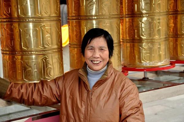 Pengzhou, China: Mujer sonriente con ruedas de oración tibetanas —  Fotos de Stock