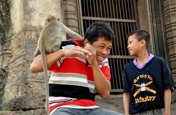 Lopburi, Tailandia: Mono en el hombro del hombre en el templo tailandés —  Fotos de Stock