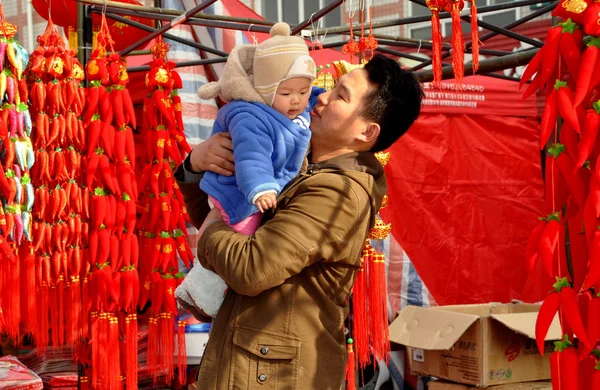 Pengzhou, China: Pai segurando filho na cabine de decorações de ano novo chinês — Fotografia de Stock