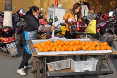 Pengzhou, China: Woman Selling Oranges from Bicycle Cart clipart