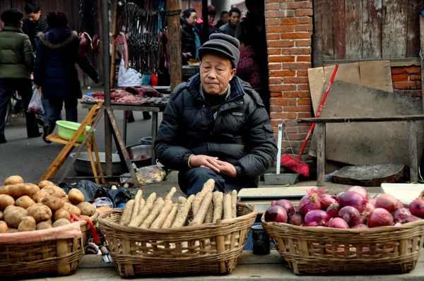 Pengzhou, China: Hombre mayor vendiendo productos en el mercado — Foto de Stock