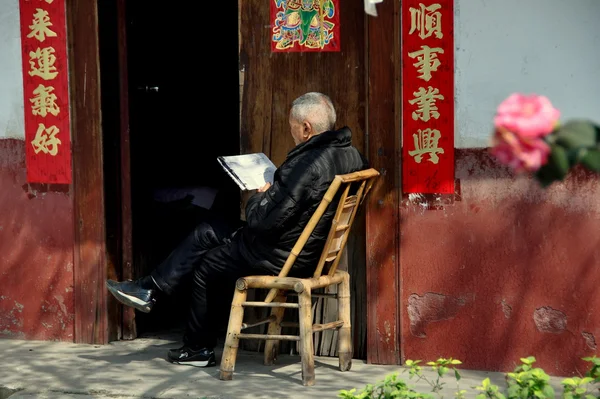 Pengzhou, Kina: äldre man läsa kinesiska tidningen — Stockfoto