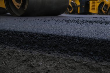Yeni bir yol inşaatında çalışan bir yol silindirinin yakın görüntüsü.