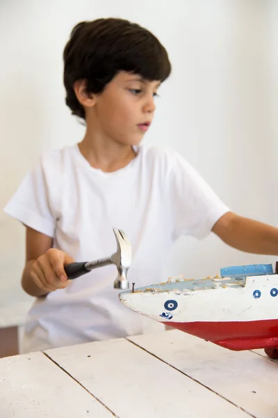 Boy painting and renovating old wooden boat — Stock Photo, Image