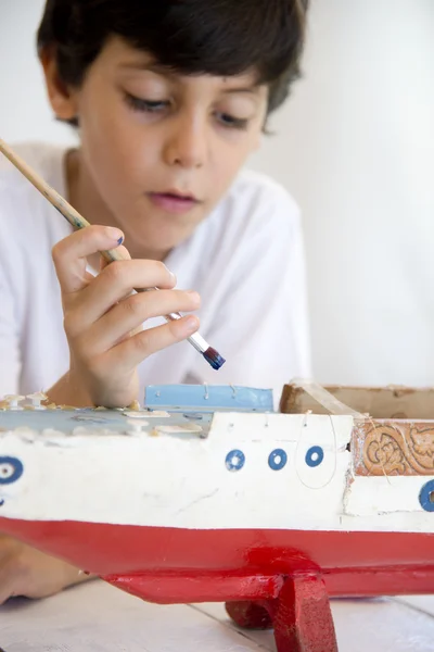 Boy painting and renovating old wooden boat — Stock Photo, Image