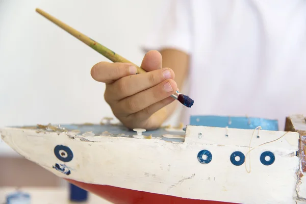 Boy painting and renovating old wooden boat — Stock Photo, Image