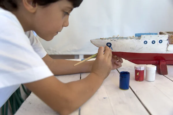 Niño pintando y renovando viejo barco de madera — Foto de Stock