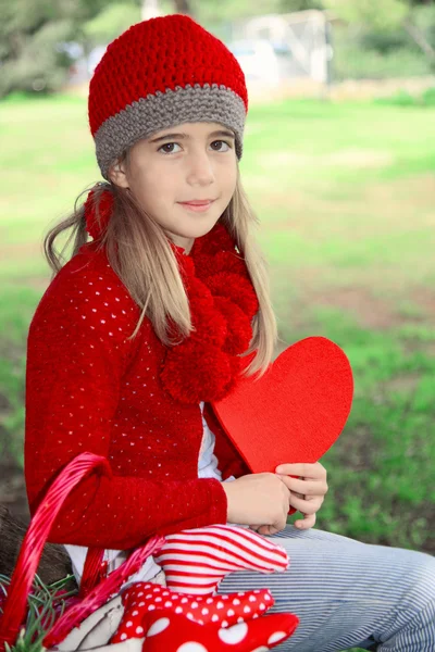 Belle fille avec chapeau au crochet rouge tenant grand coeur de feutre Valentine — Photo