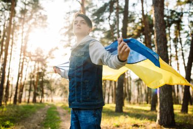 Ukrayna bayrağı taşıyan çocuk. Bağımsızlık kavramı. Rüzgarda sallanan sarı-mavi bir bayrak. Rus saldırısını durdurun. Savaşı durdurun.
