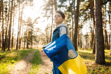 Ukrayna bayrağı taşıyan çocuk. Bağımsızlık kavramı. Rüzgarda sallanan sarı-mavi bir bayrak. Rus saldırısını durdurun. Savaşı durdurun.