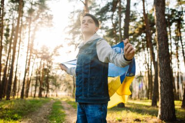 Ukrayna bayrağı taşıyan çocuk. Savaşa karşı genç bir adam. Ukrayna 'ya özgürlük. Bağımsızlık kavramı. Rüzgarda dalgalanan sarı-mavi bir bayrak