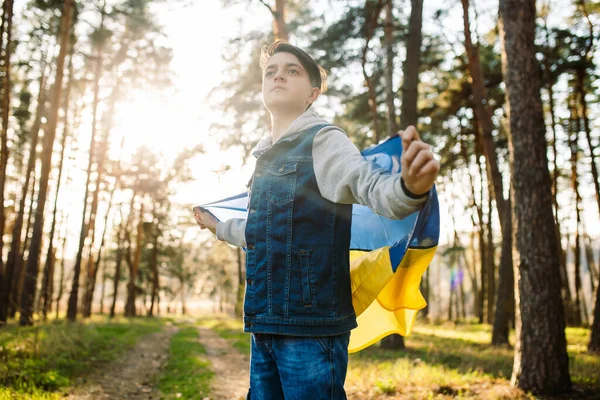 Ukrayna bayrağı taşıyan çocuk. Savaşa karşı genç bir adam. Ukrayna 'ya özgürlük. Bağımsızlık kavramı. Rüzgarda dalgalanan sarı-mavi bir bayrak