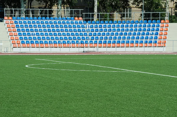 Gressfelt og plastikkseter på stadion, åpne dører sport – stockfoto