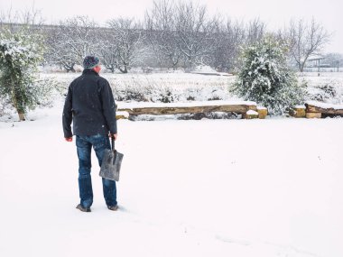 Kar fırtınasından sonra patikadan kar temizleyen kürekli bir adam. Kış konsepti