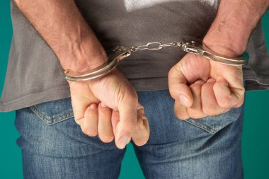 Elleri arkada olan tutuklu bir adam. Pantolon giymiş kelepçeli bir adamın görüntüsü, insan hakları kavramı..