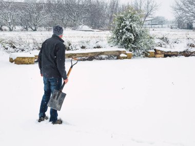 Kar fırtınasından sonra patikadan kar temizleyen kürekli bir adam. Kış konsepti