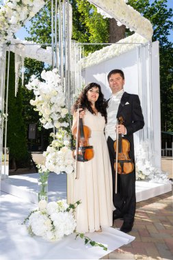 Düğün kemeri geçmişi olan kadın ve erkek kemancılar.