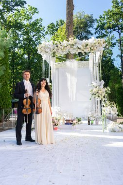 Düğün kemeri geçmişi olan kadın ve erkek kemancılar.