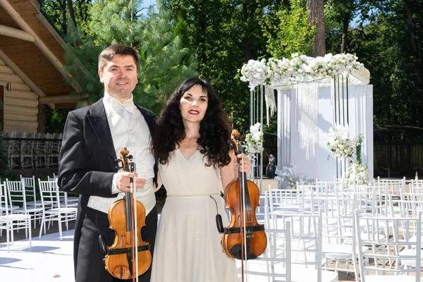 Düğün kemeri geçmişi olan kadın ve erkek kemancılar.