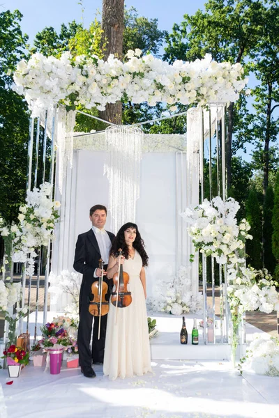 Düğün kemeri geçmişi olan kadın ve erkek kemancılar.