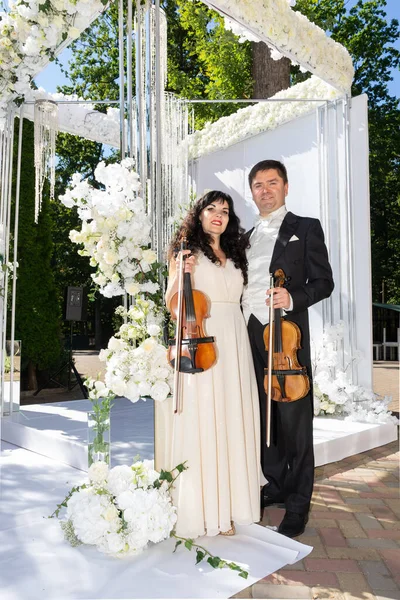 Düğün kemeri geçmişi olan kadın ve erkek kemancılar.
