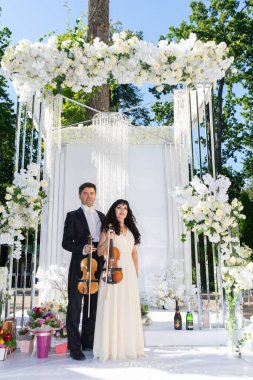 Düğün kemeri geçmişi olan kadın ve erkek kemancılar.