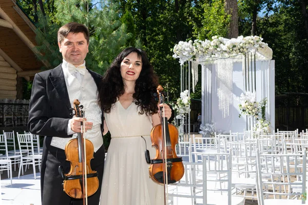 Düğün kemeri geçmişi olan kadın ve erkek kemancılar.