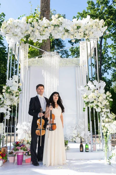 Düğün kemeri geçmişi olan kadın ve erkek kemancılar.