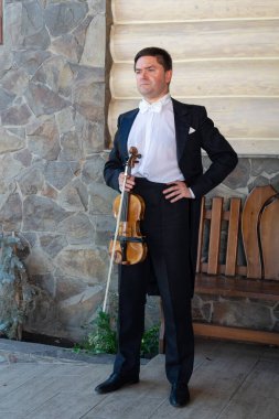 Kemancı ve kemancı binanın yanında duruyor..