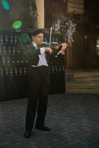 バイオリニストが店の入り口でバイオリンを弾く — ストック写真