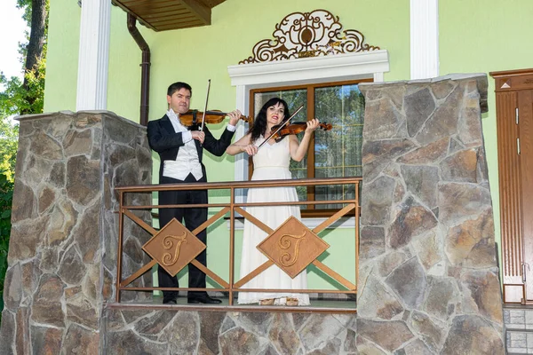 Kemancı ve kemancı eski bir evin verandasında keman çalıyorlar..