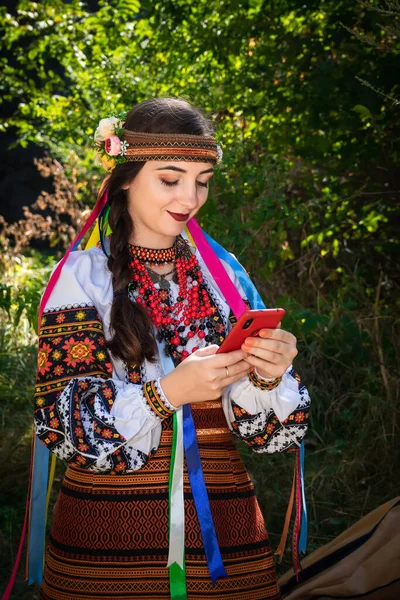 身穿绣花衬衫的乌克兰妇女手里拿着一部手机 — 图库照片