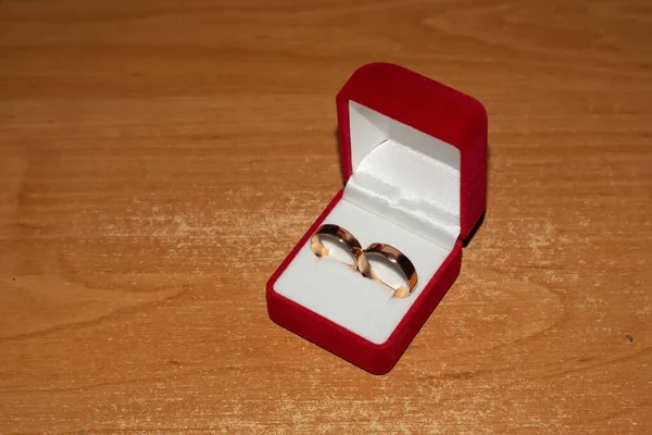 Wedding rings of brides in a red box for wedding rings on a wooden table.