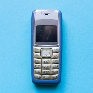 Mavi arkaplanda eski mavi düğmeli cep telefonu.
